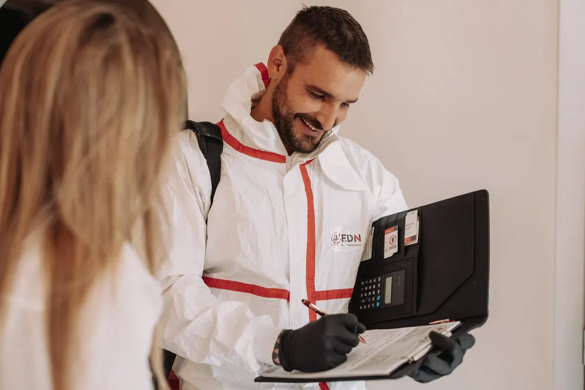 Technicien EDN en combinaison remplissant un rapport devant une cliente